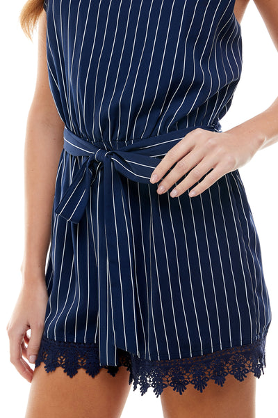 Maggie Sleeveless Romper in Navy pinstripe. Self belt tie Lace trim on hem line. Back hidden zipper closure.